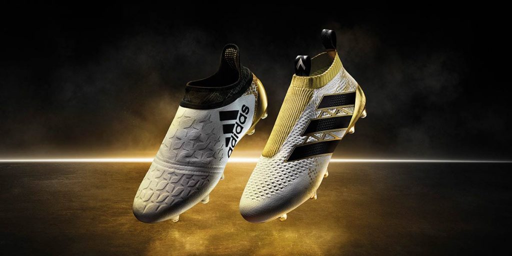 Paire de chaussures de football adidas blanches et dorées sur fond noir