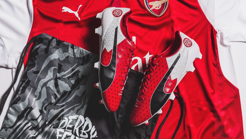 Chaussure de football Puma rouge et blanche posée sur des maillots rouges