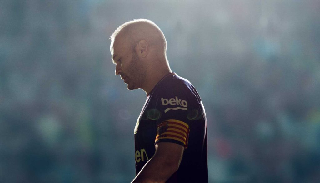 Joueur du FC Barcelone de dos, tête baissée, dans une lumière sombre