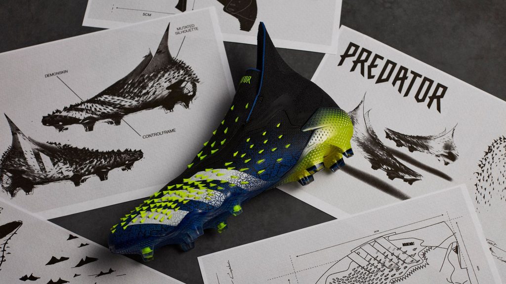 Chaussure de football adidas Predator Freak noire et jaune posée sur des dessins