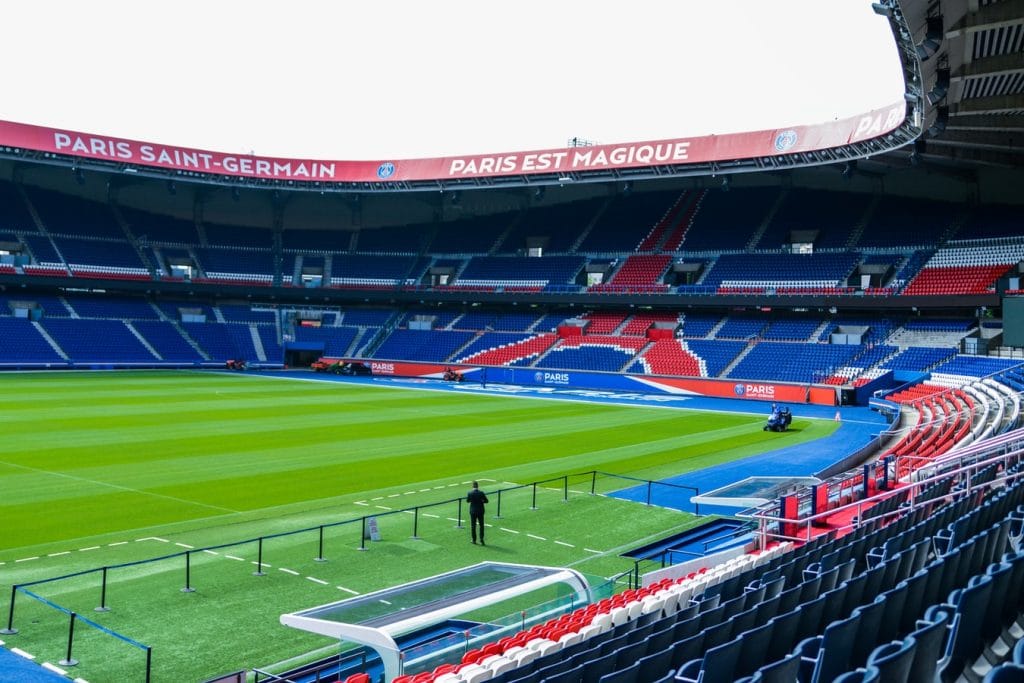 Tribunes rouges et bleues et pelouse d’un stade de football