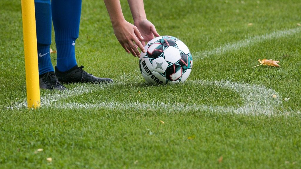 Joueur posant un ballon au point de corner d’un terrain de football