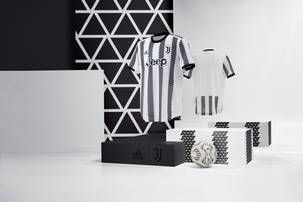 Maillot domicile 2022-2023 de la Juventus à rayures noires et blanches, exposé dans un décor graphique noir et blanc