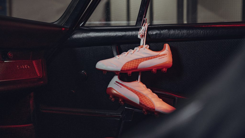 Paire de chaussures de football Puma King blanches et orange posées dans l’habitacle d’une voiture